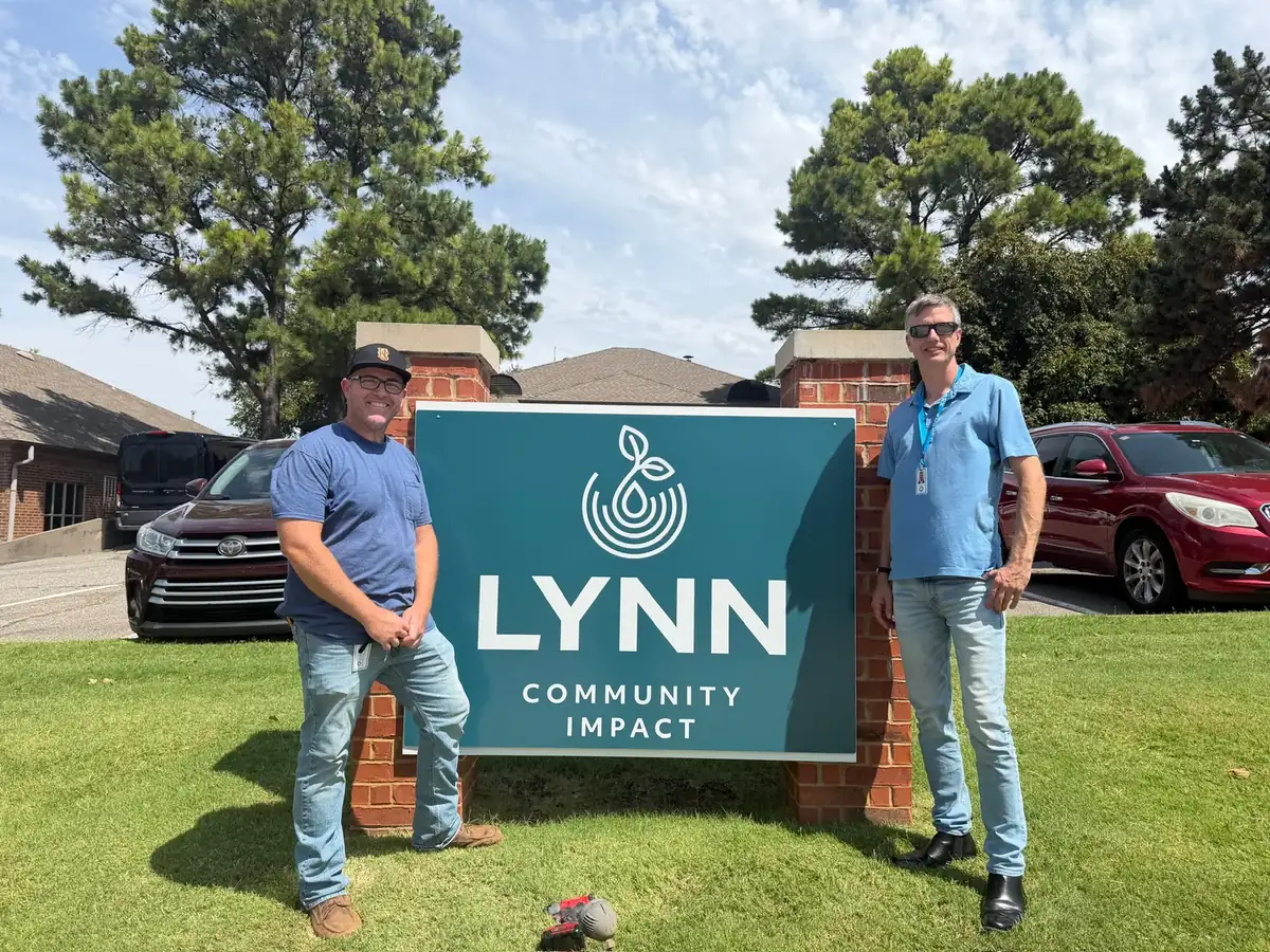 Lynn Community Impact team members beside the garden entrance sign